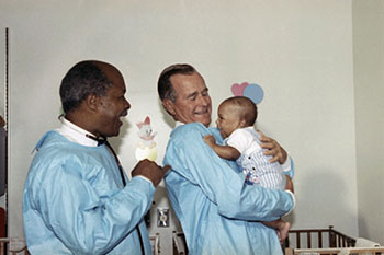 President George H.W. Bush visits a Washington, DC, hospital ward for infants abandoned by drug-addicted mothers, with Dr. Louis Sullivan in 1989. (Barry Thumma. AP Images)